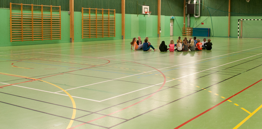 Lapset istuvat Värnan koulun urheiluhallin lattialla